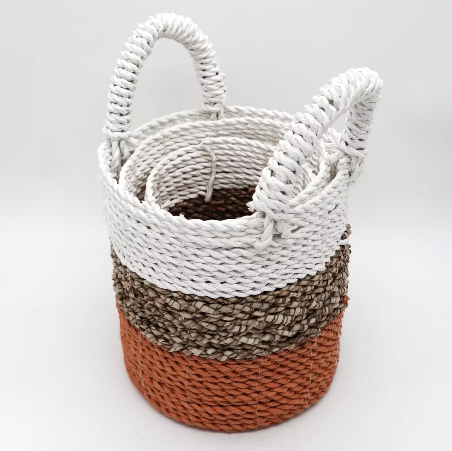 Stack of woven baskets with white, brown, and orange colors on a light gray background