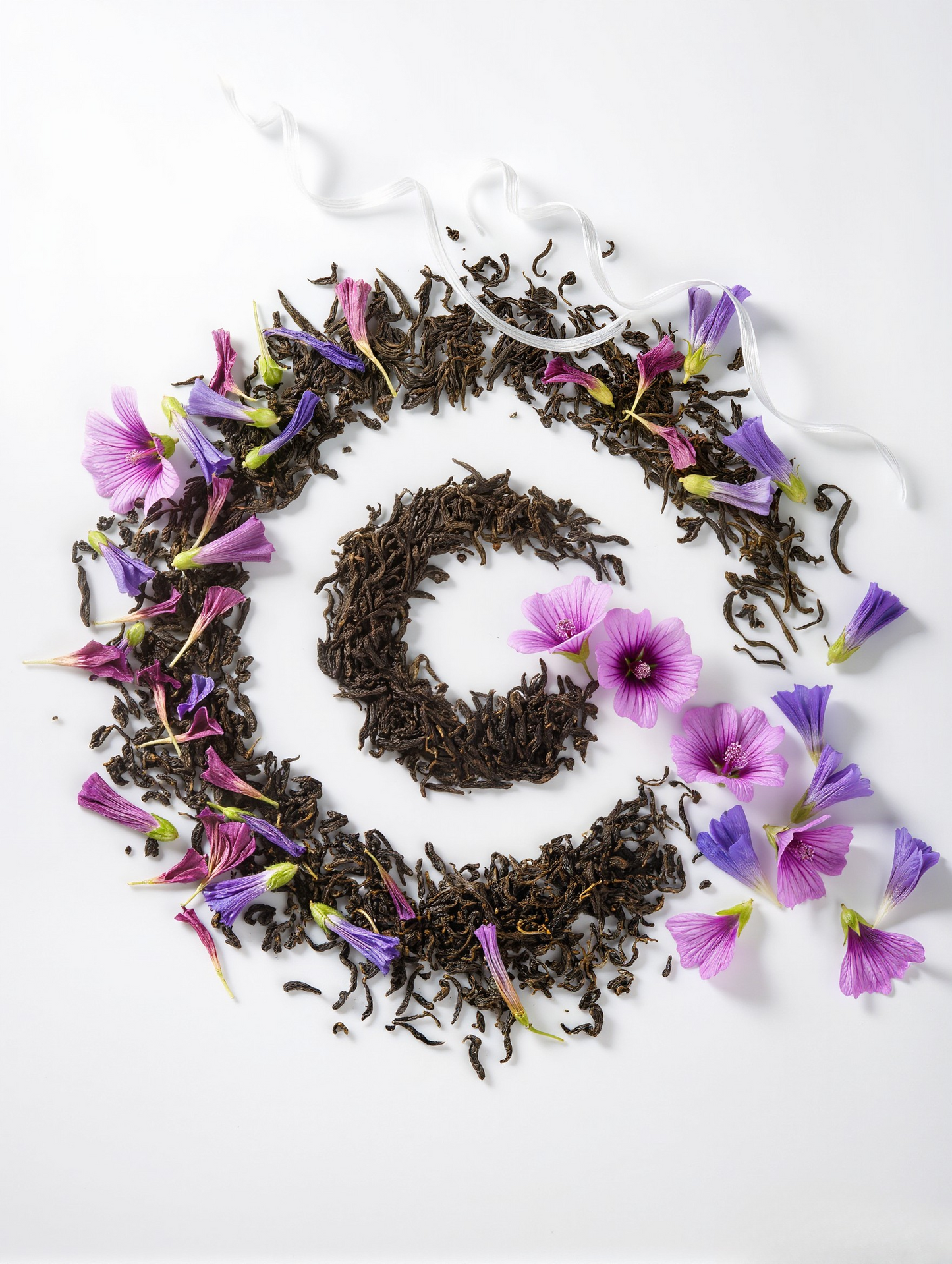 Tea leaves and purple flowers arranged in a circular pattern on a white background