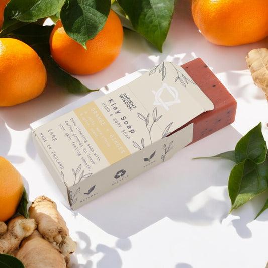 Orange & Ginger clay soap bar beside fresh citrus and ginger root