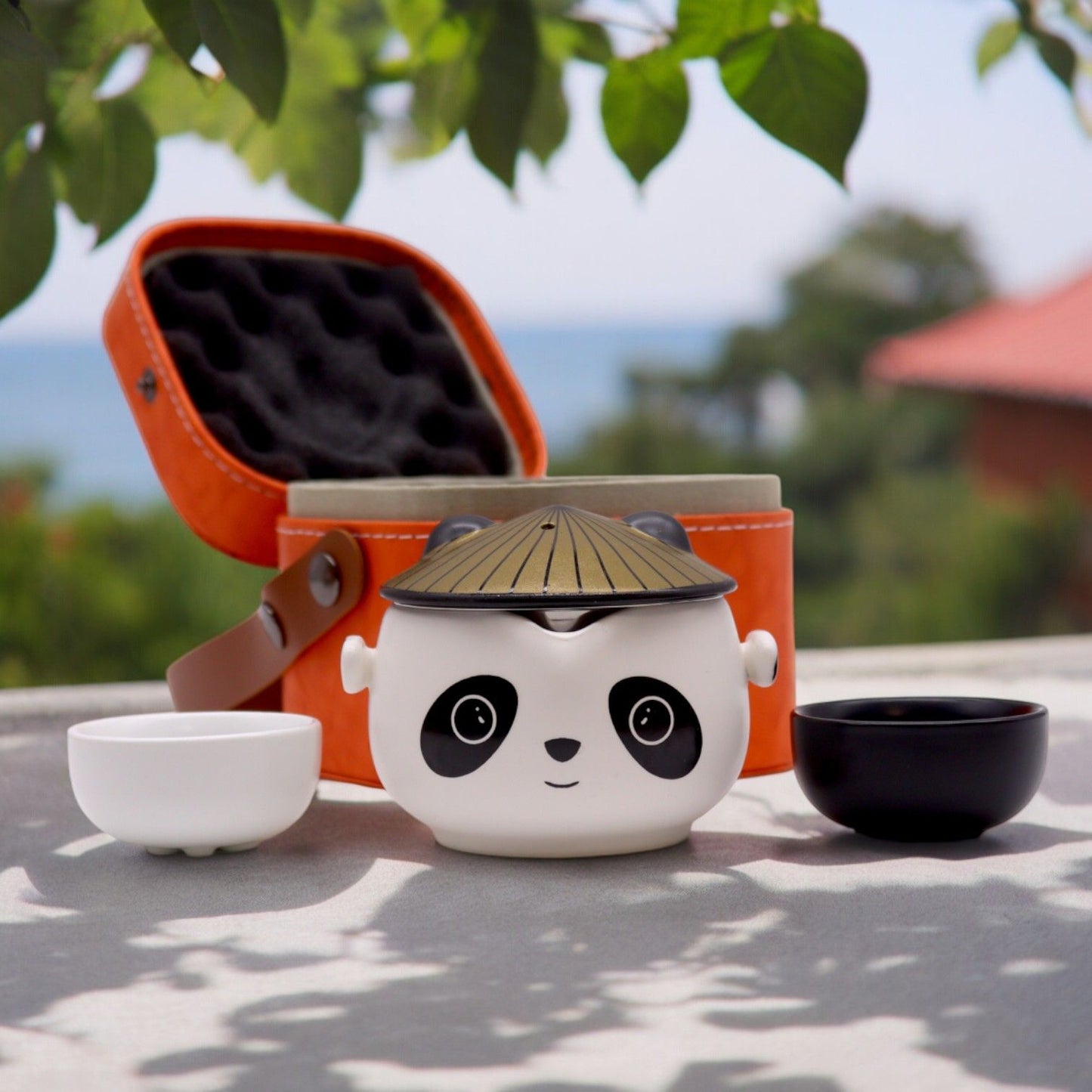 Ceramic panda tea set with a bamboo lid on a table outdoors.