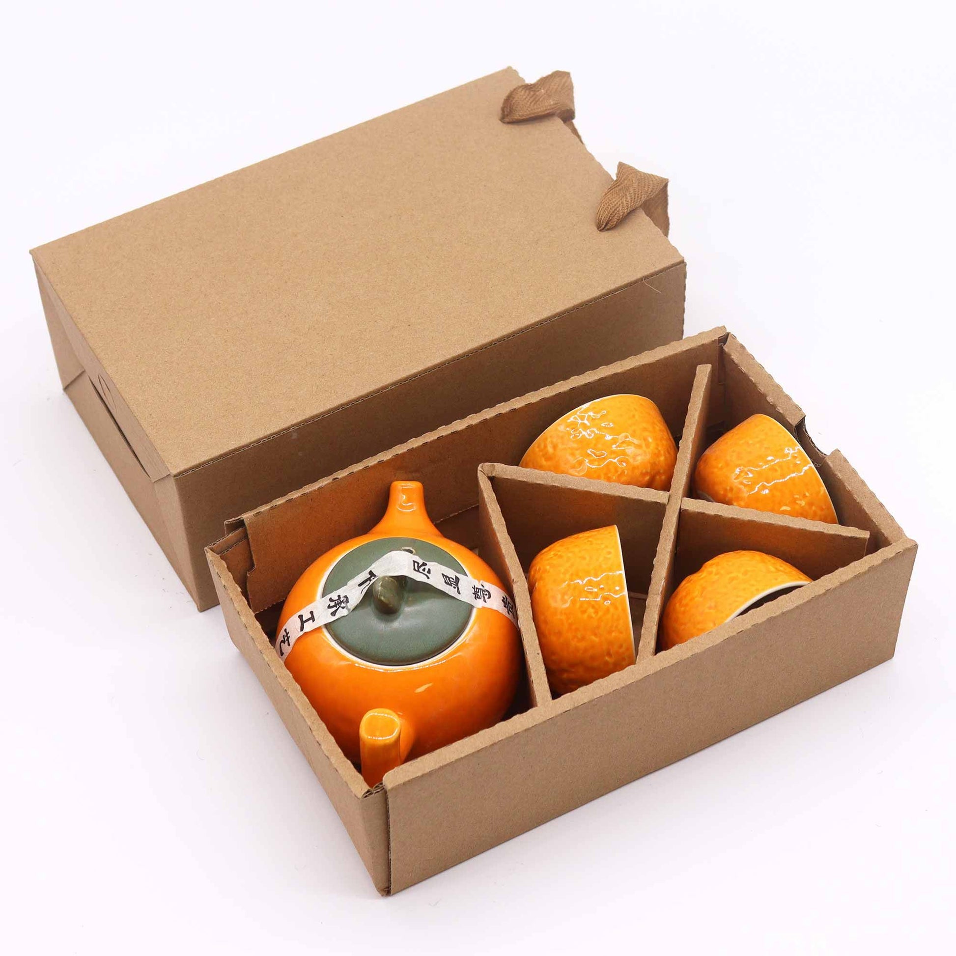 Ceramic orange-shaped containers with a green base in a cardboard box on a white background