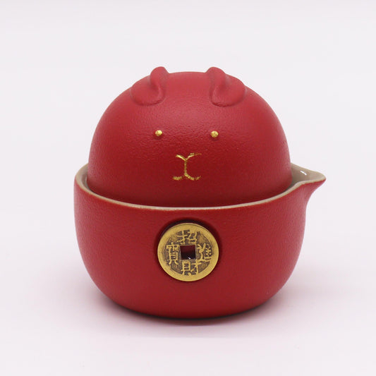 Red teapot with a lid shaped like a bear on a light pink background