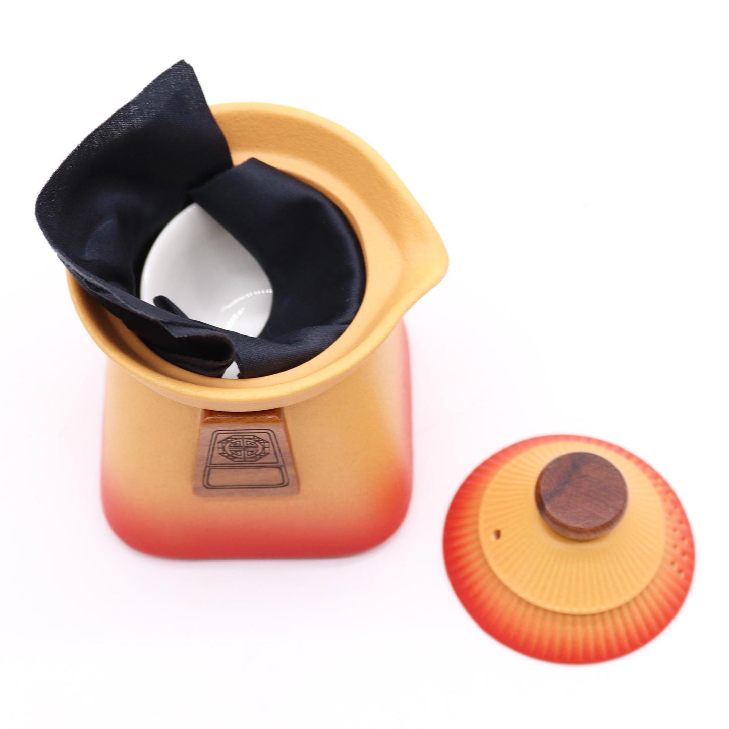 Orange and red ceramic teapot with black interior on a white background