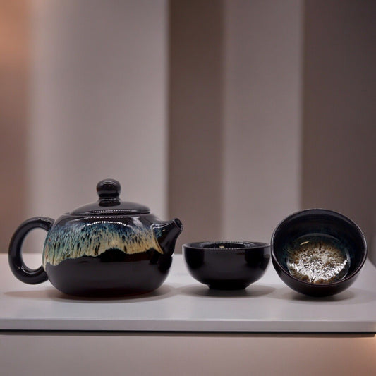 Ceramic teapot and two cups on a light surface with a neutral background