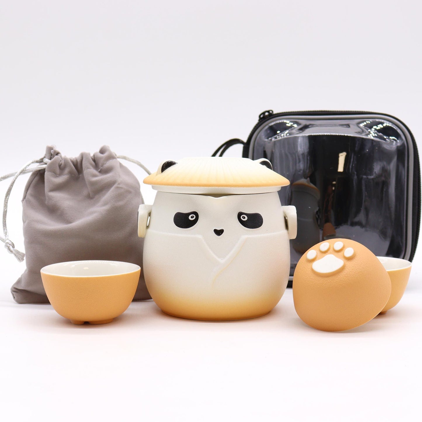 Ceramic cat-shaped container with small bowls and a black bag on a white background