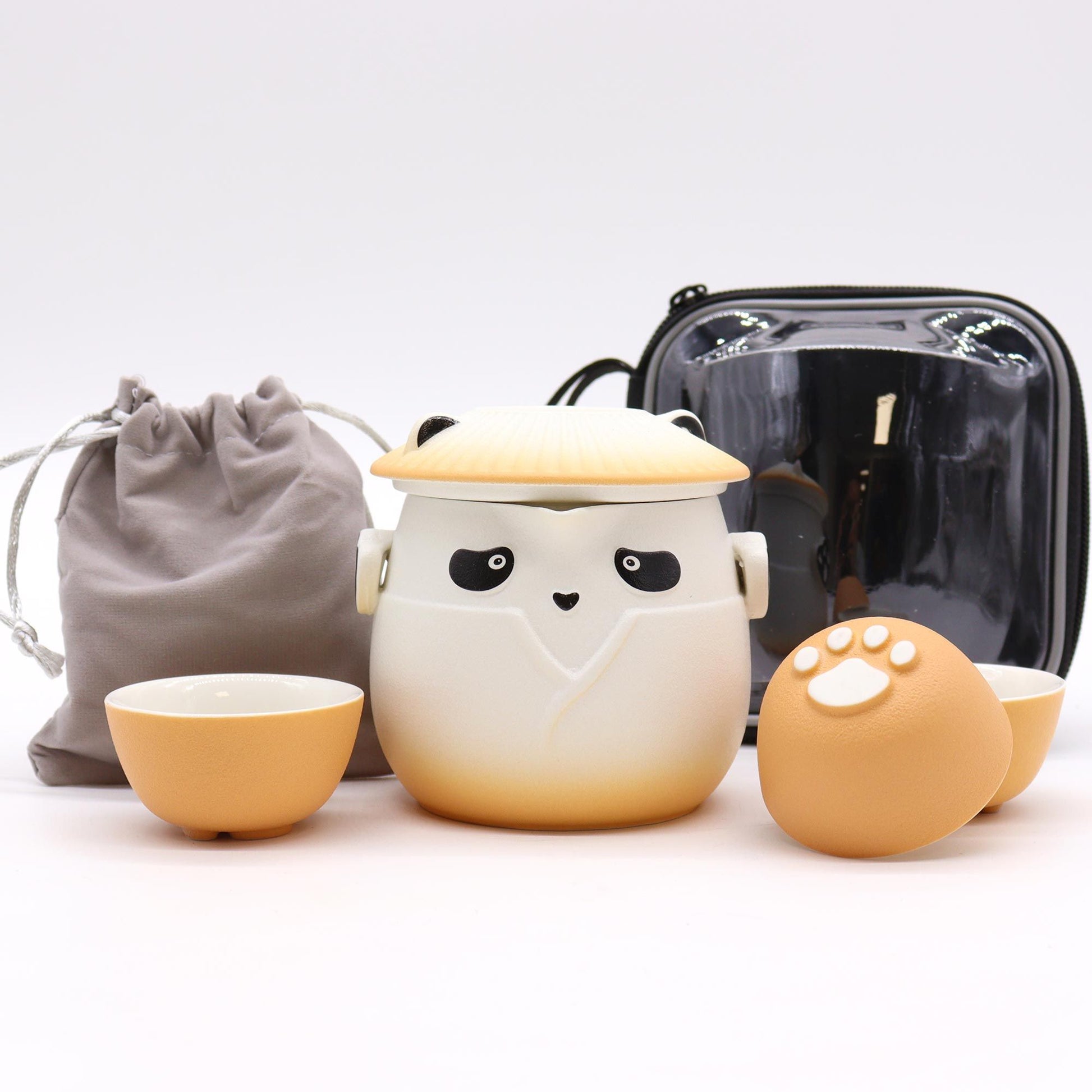Ceramic cat-shaped container with small bowls and a black bag on a white background