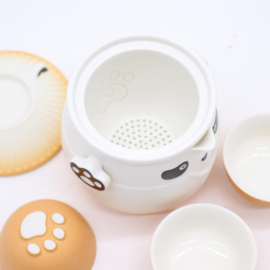 White ceramic tea infuser with paw print design on a light pink background